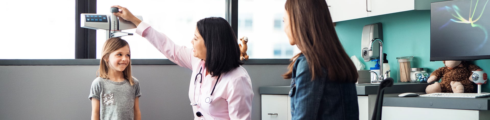 Doctor measuring little girl in exam room